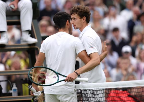 Carlos Alcaraz of Spain (obscured) meets Ugo Humbert of France at the net following victory in his Gentleman's Singles fourth round match during day seven of The Champio<em></em>nships Wimbledon 2024 at All England Lawn Tennis and Croquet Club on July 07, 2024 in London, England.